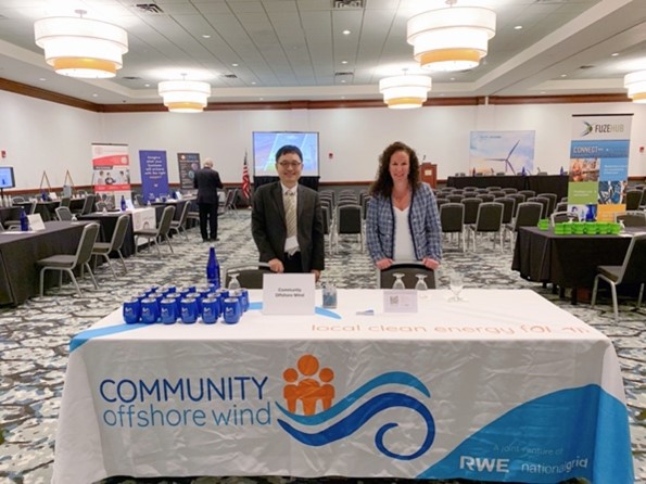 A promotional event featuring a table with 'COMMUNITY offshore wind' and blue items, focused on renewable energy.