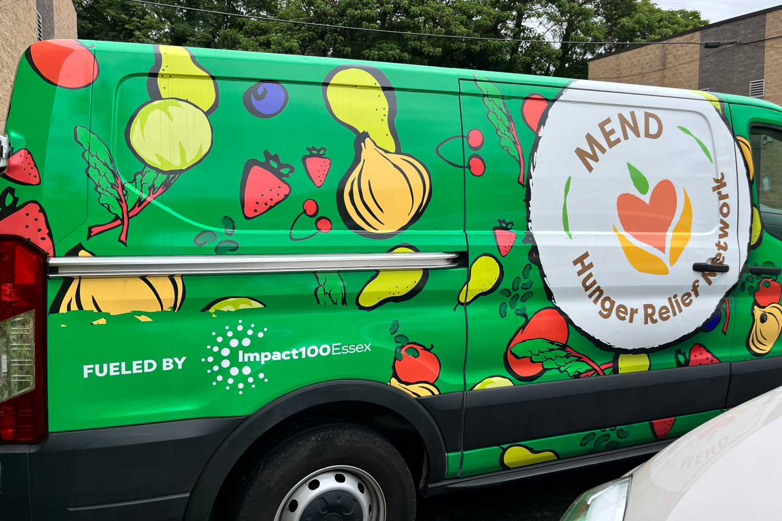 A green van decorated with colourful fruits and vegetables, featuring the logo of MEND Hunger Relief Network.