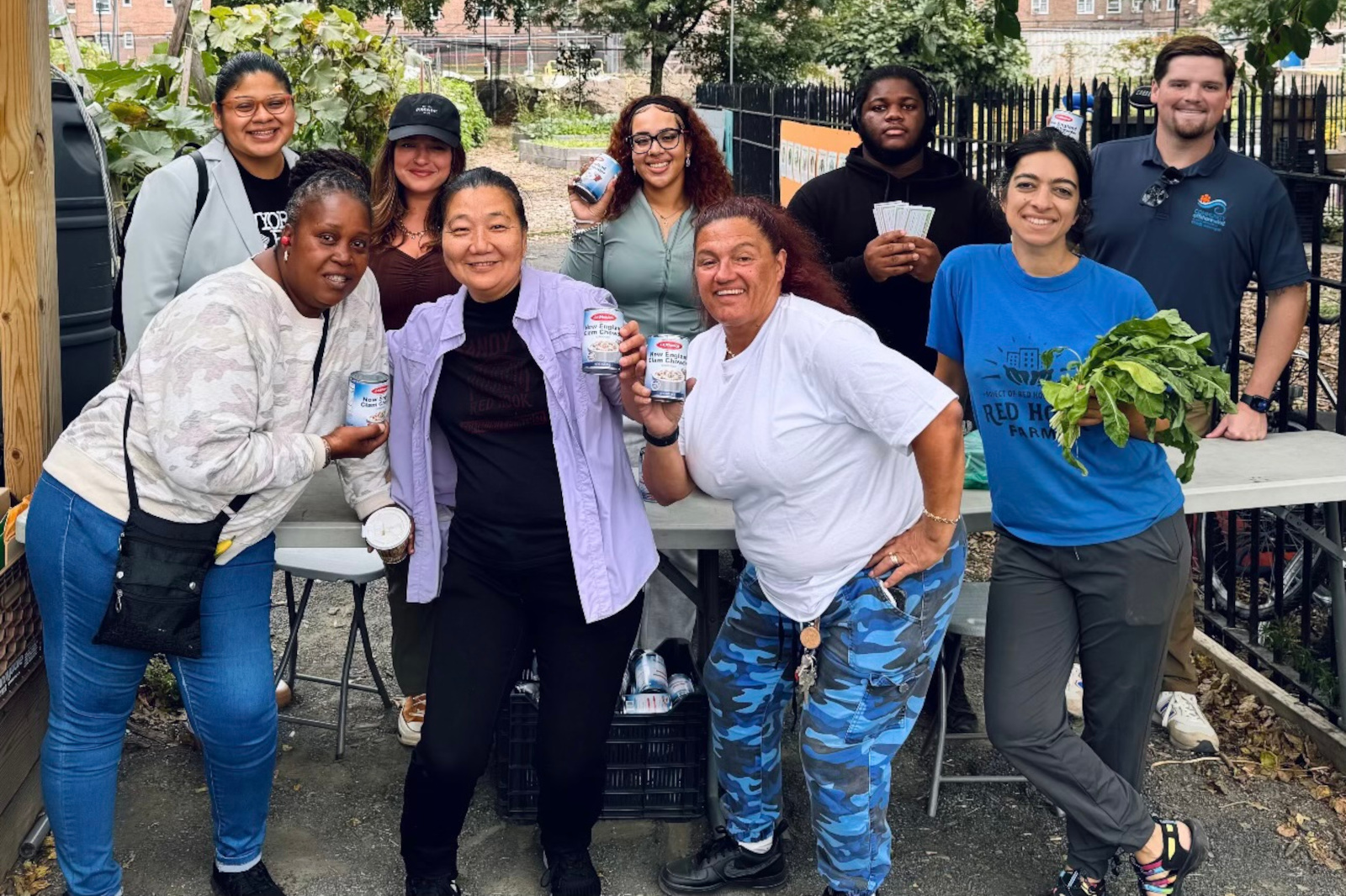 A group of people posing with food items at an outdoor gathering, showcasing community spirit and cooperation.